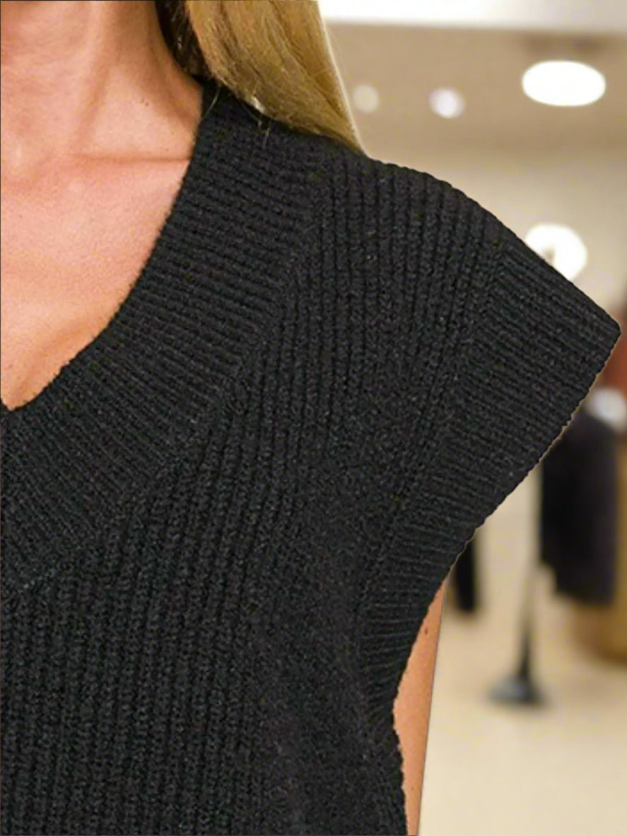 Black sleeveless knitted top worn by a person on a white background