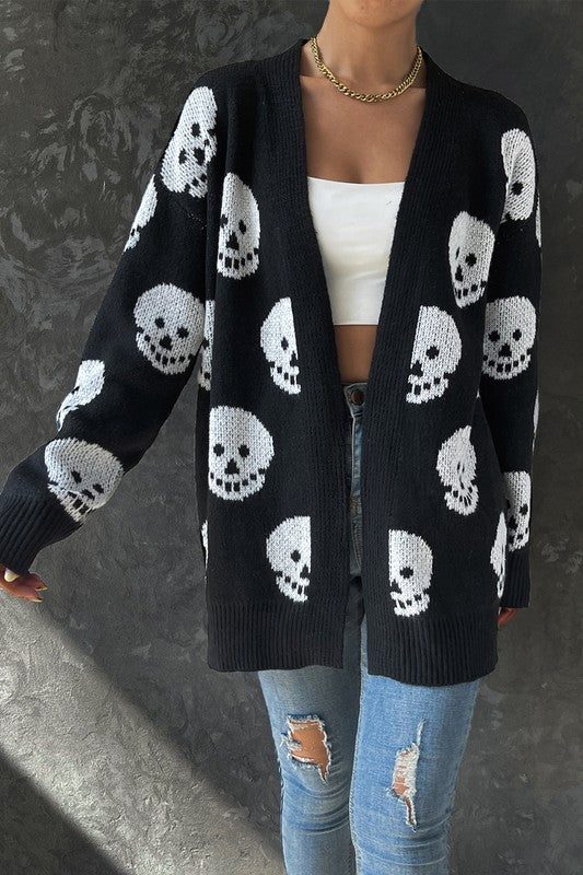 Person wearing a black cardigan with white skull patterns on a dark background