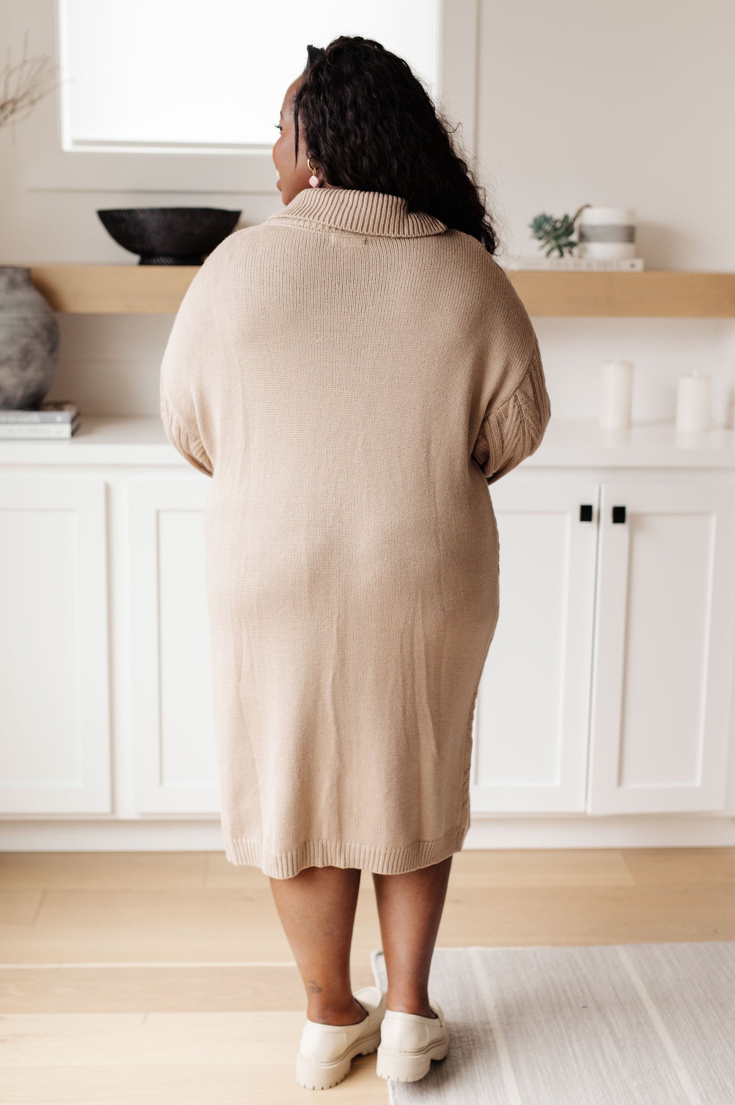 Person wearing a beige sweater in a kitchen setting