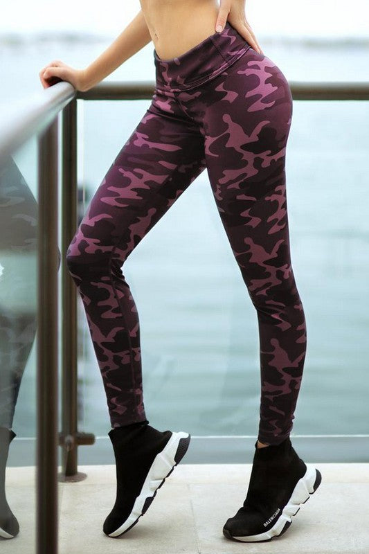 Person wearing purple camouflage leggings standing by a railing with water in the background