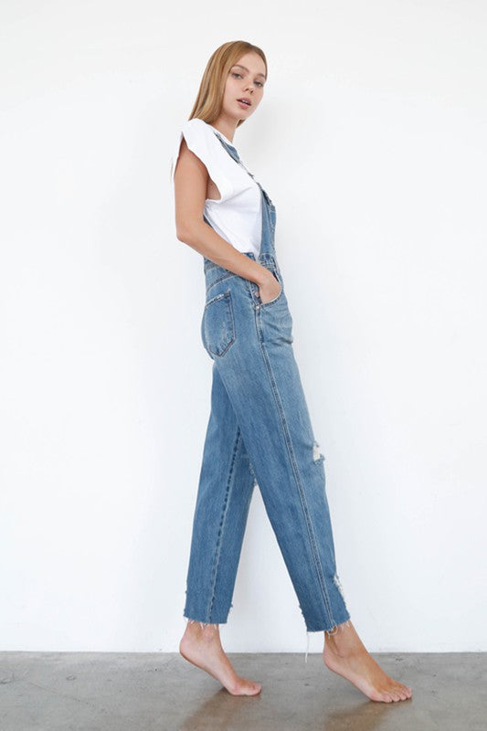 Woman wearing a denim jumpsuit against a white background