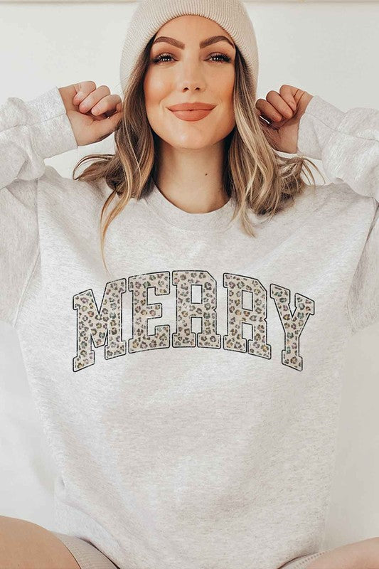 Person wearing a white sweatshirt with 'MERRY' printed in leopard print on a plain background