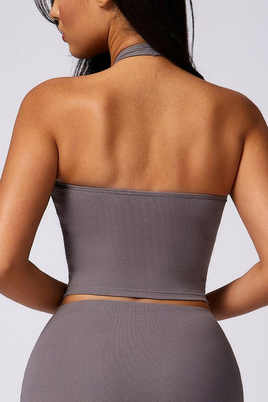 Person wearing a gray tube top and high-waisted leggings against a light gray background