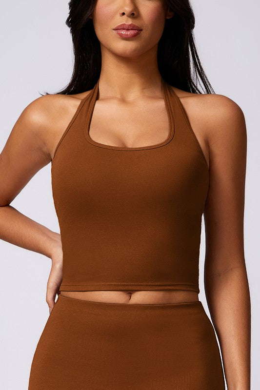 Woman wearing a brown halter top and skirt set against a plain background