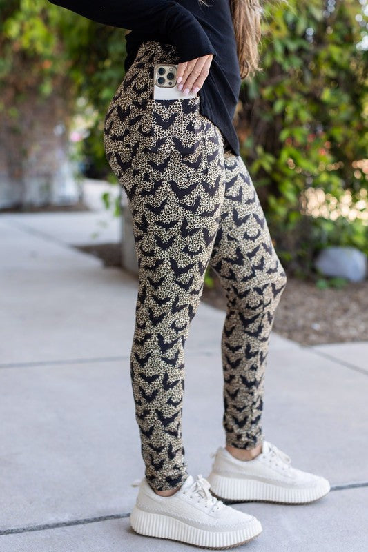 Person wearing patterned pants and white sneakers on a sidewalk.