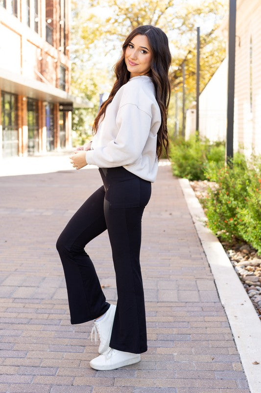 Woman in a white sweater and black pants walking on a sidewalk.