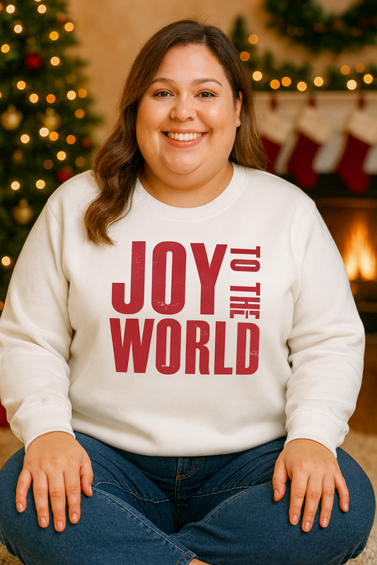 Person wearing a white sweatshirt with 'Joy to the World' text, sitting in front of a Christmas tree and stockings.