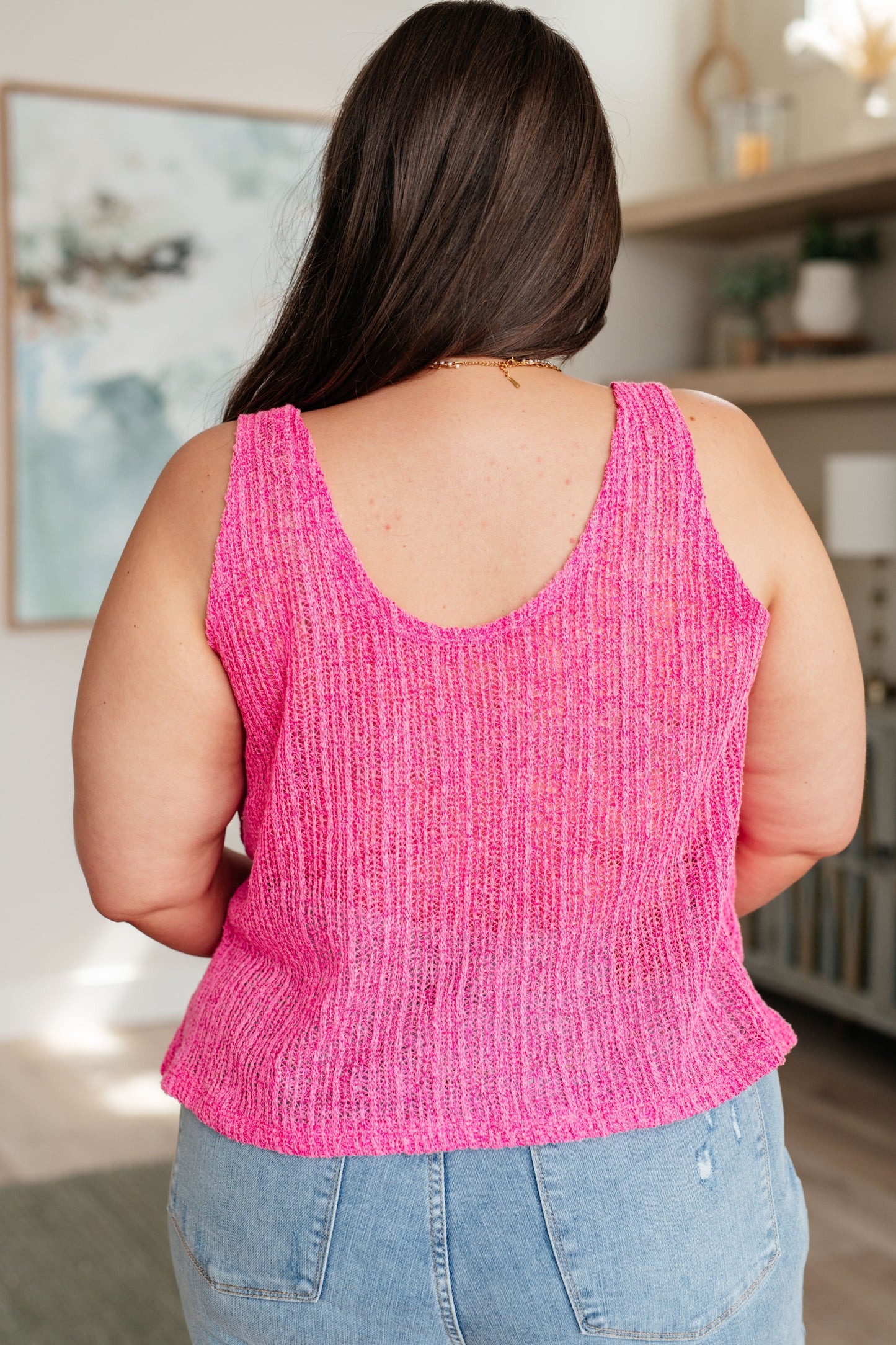 A woman wearing a pink knit V-neck tank top with an A-line silhouette.