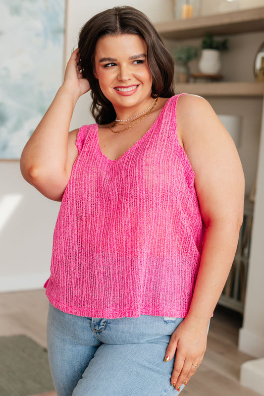 A woman wearing a pink knit V-neck tank top with an A-line silhouette.