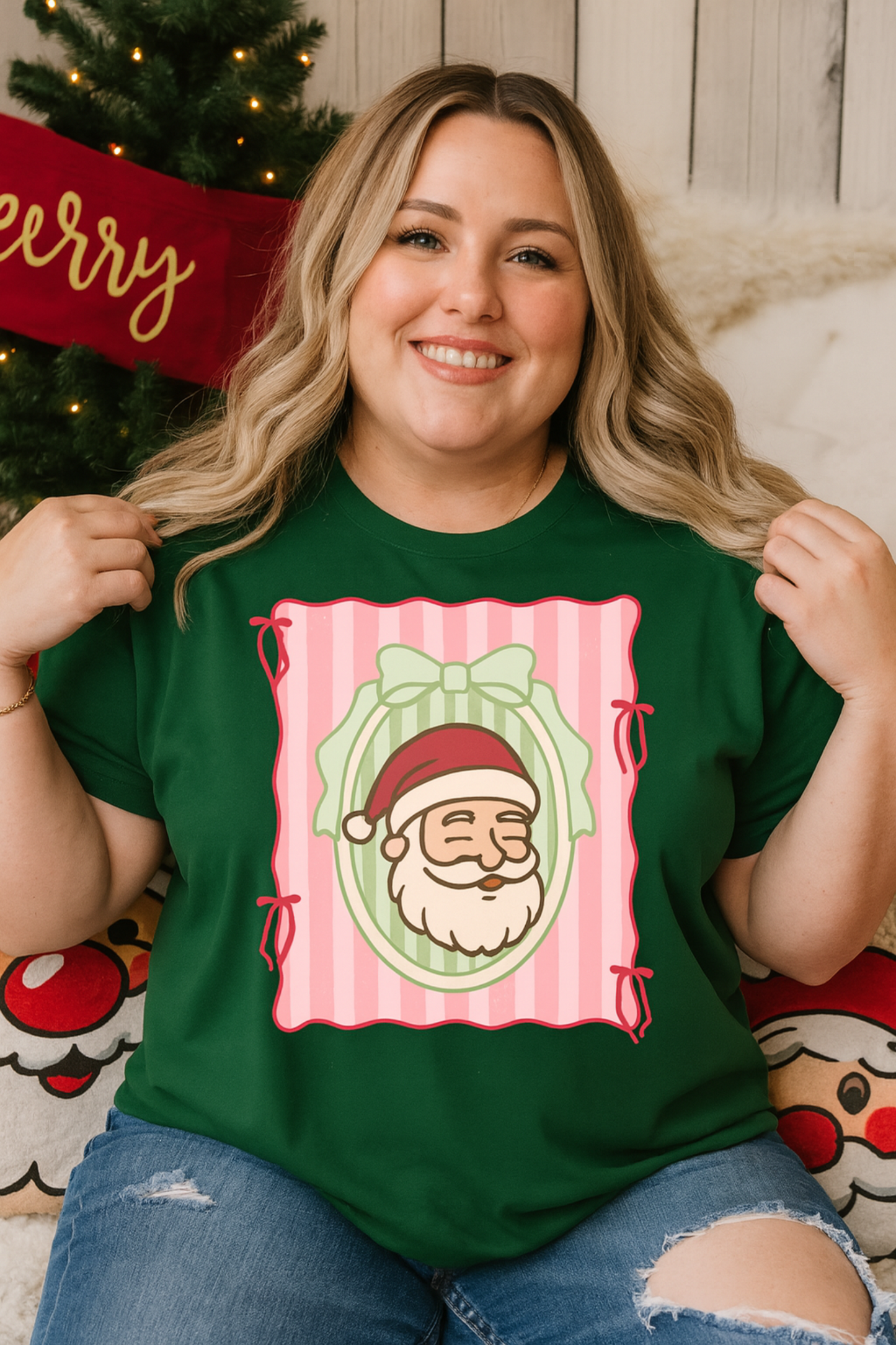 Woman wearing a green t-shirt with a Christmas design, standing in front of a decorated Christmas tree.
