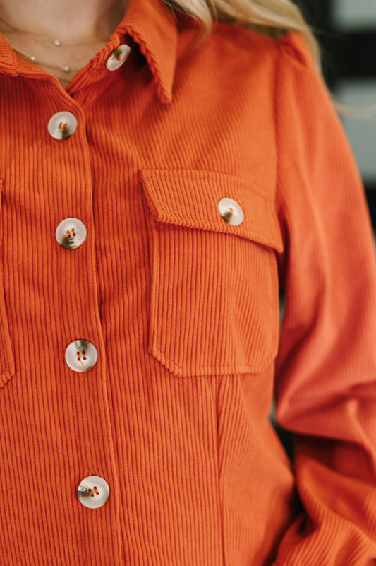 Close-up of an orange corduroy shirt with buttons and a pocket.