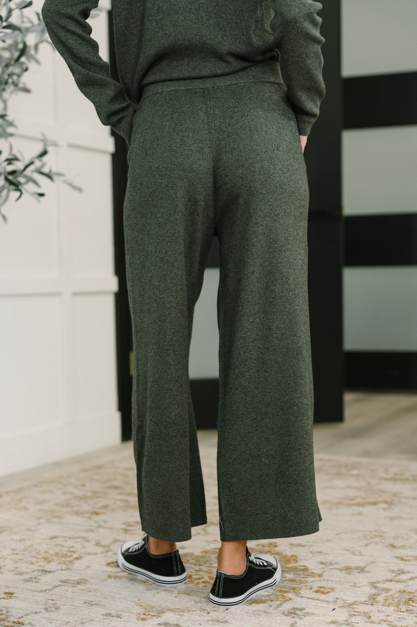 Person wearing green pants and a dark sweater with a blurred background