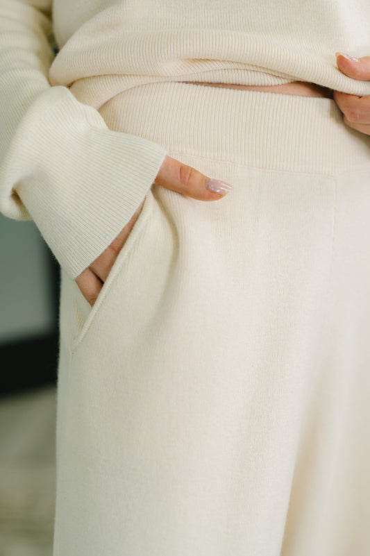 Close-up of a person wearing a cream-colored sweater with a blurred background