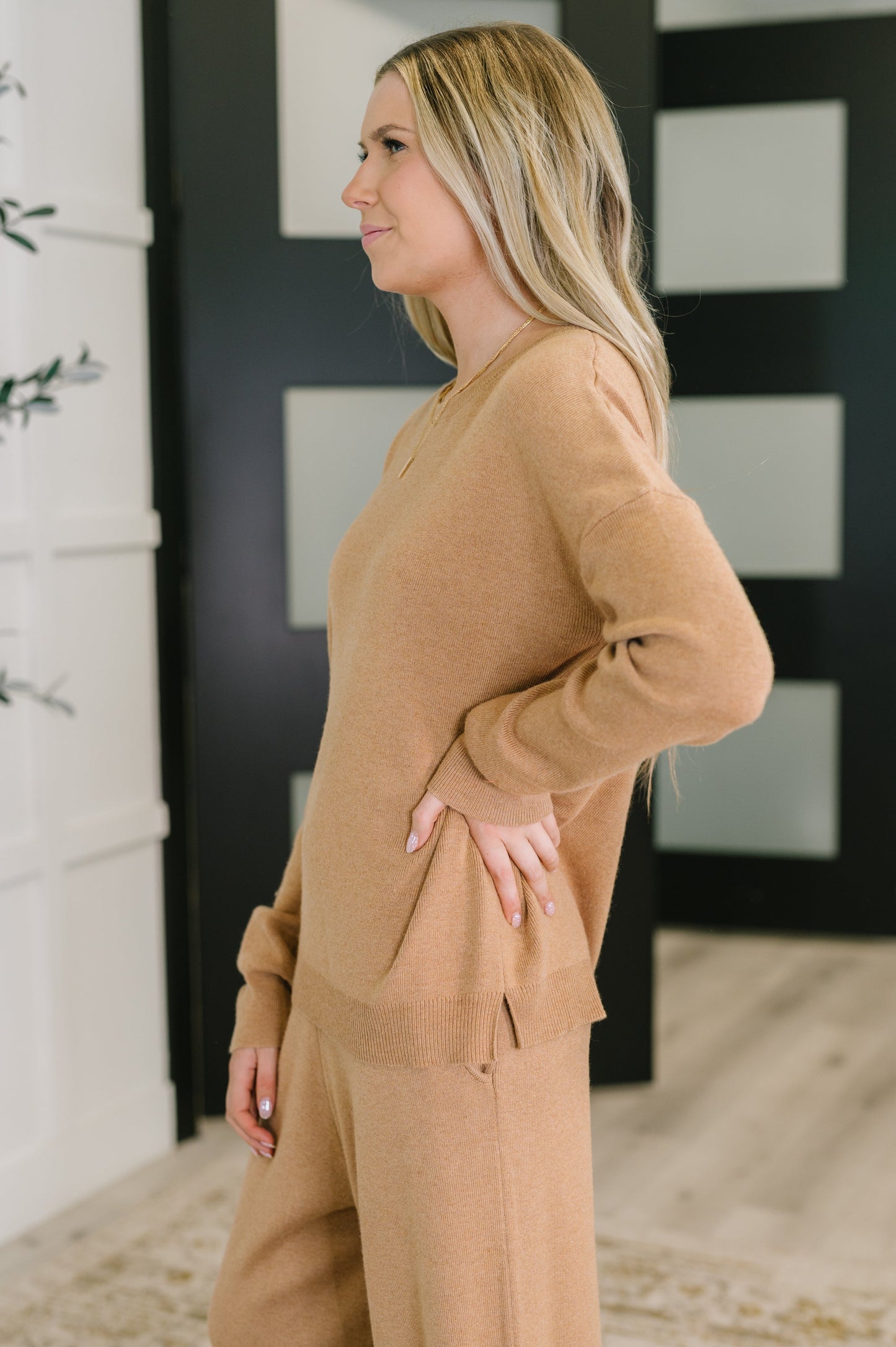Woman wearing a beige sweater and pants in a room with a black and white abstract painting on the wall.