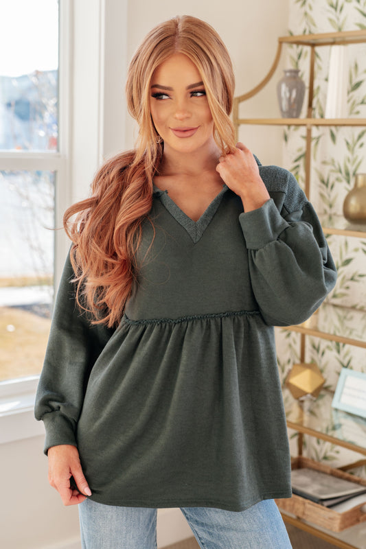 Woman wearing a green oversized sweater in a room with decor elements.