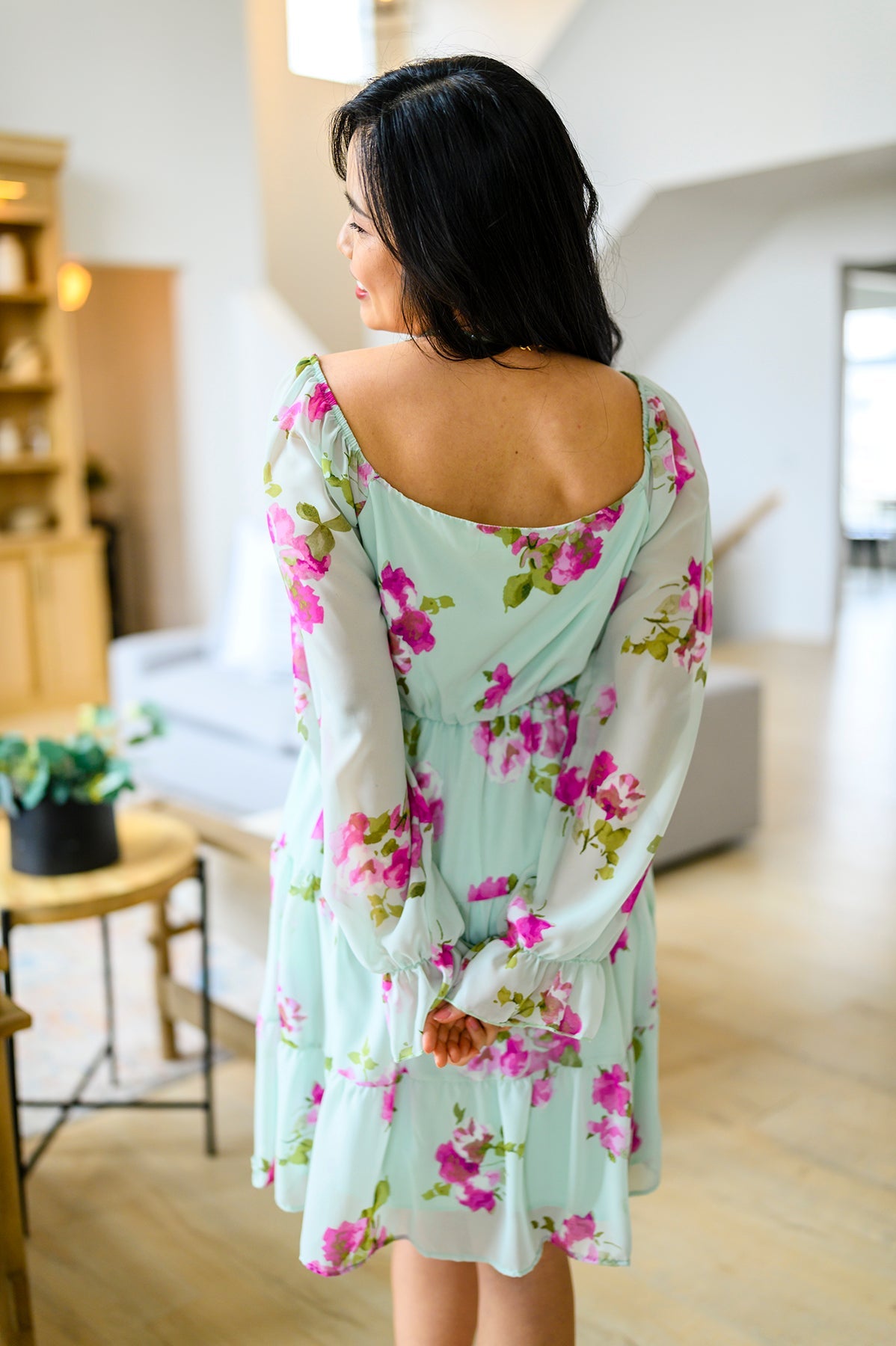 Woman wearing a floral dress in a modern living room.