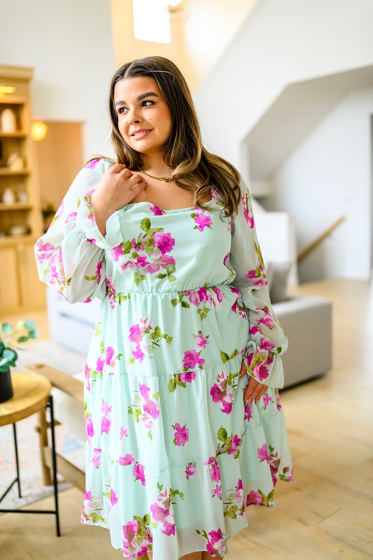 Woman wearing a floral dress in a modern living room.