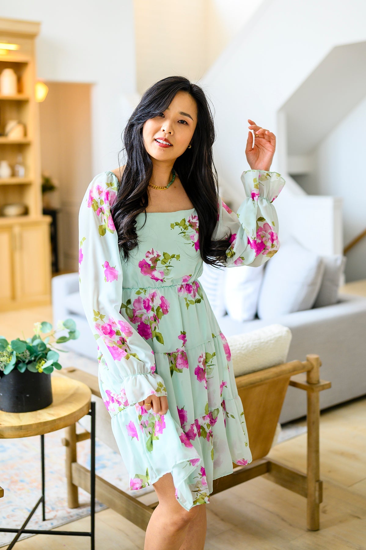 Woman in a floral dress sitting in a modern living room.