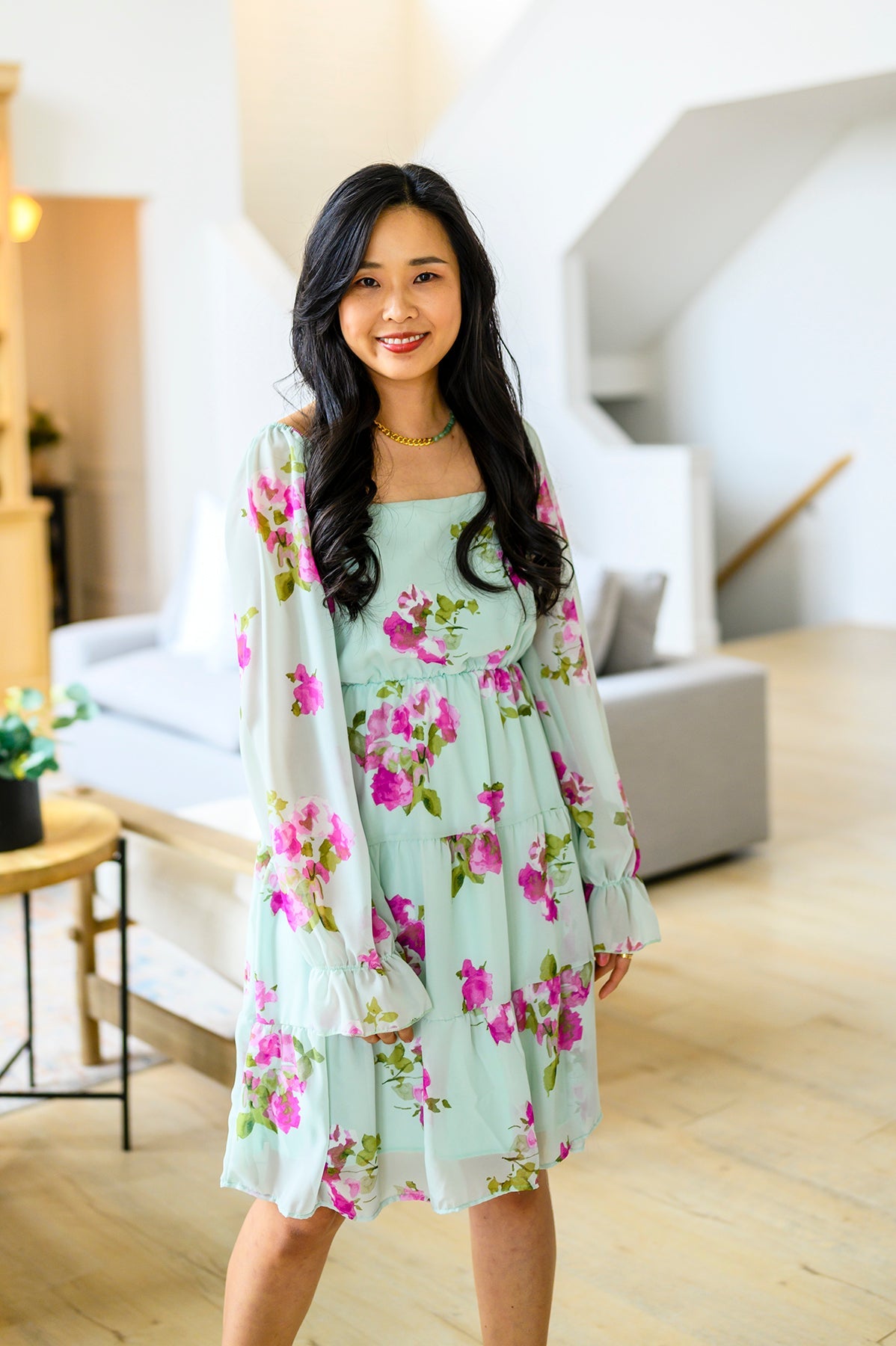 Woman wearing a light blue floral dress in a modern living room.