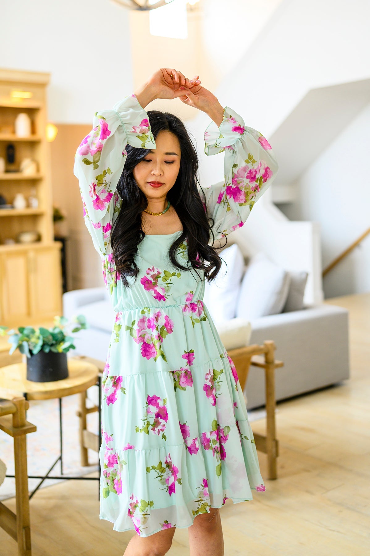 Woman in a floral dress posing in a living room.