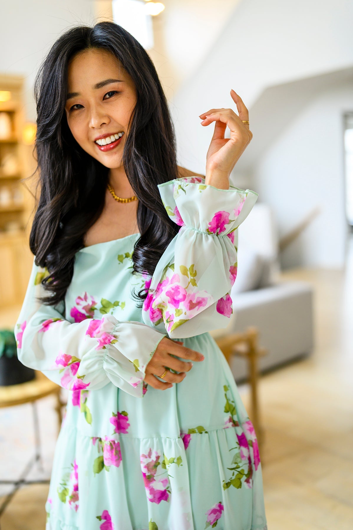 Woman in a floral dress posing in a blurred indoor setting