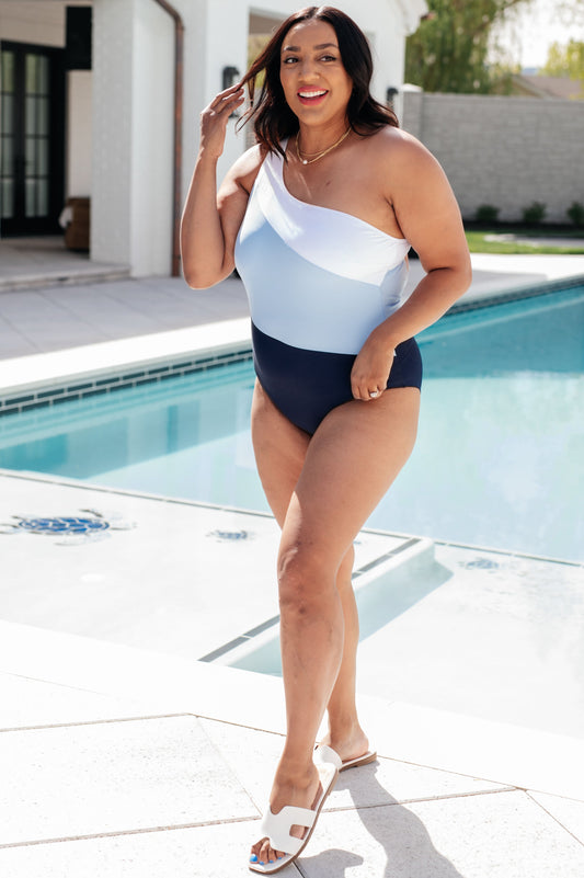 Woman in a colorful one-piece swimsuit standing by a pool.