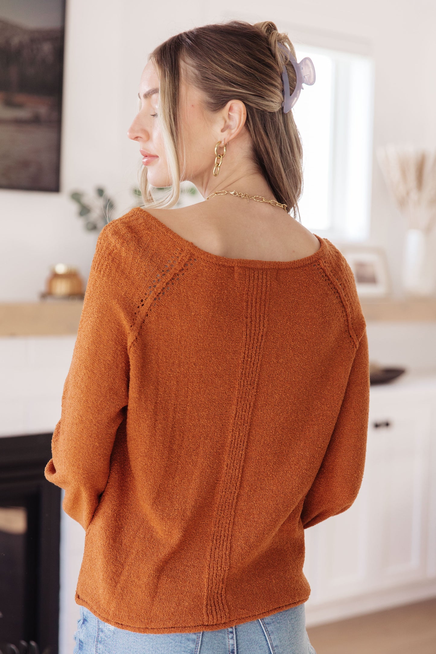 Woman wearing a rust-colored sweater in an indoor setting