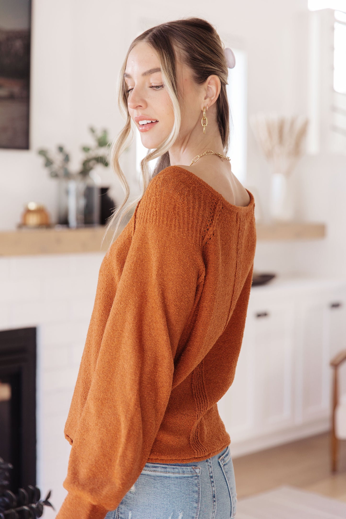 Woman wearing a rust-colored sweater in a kitchen setting