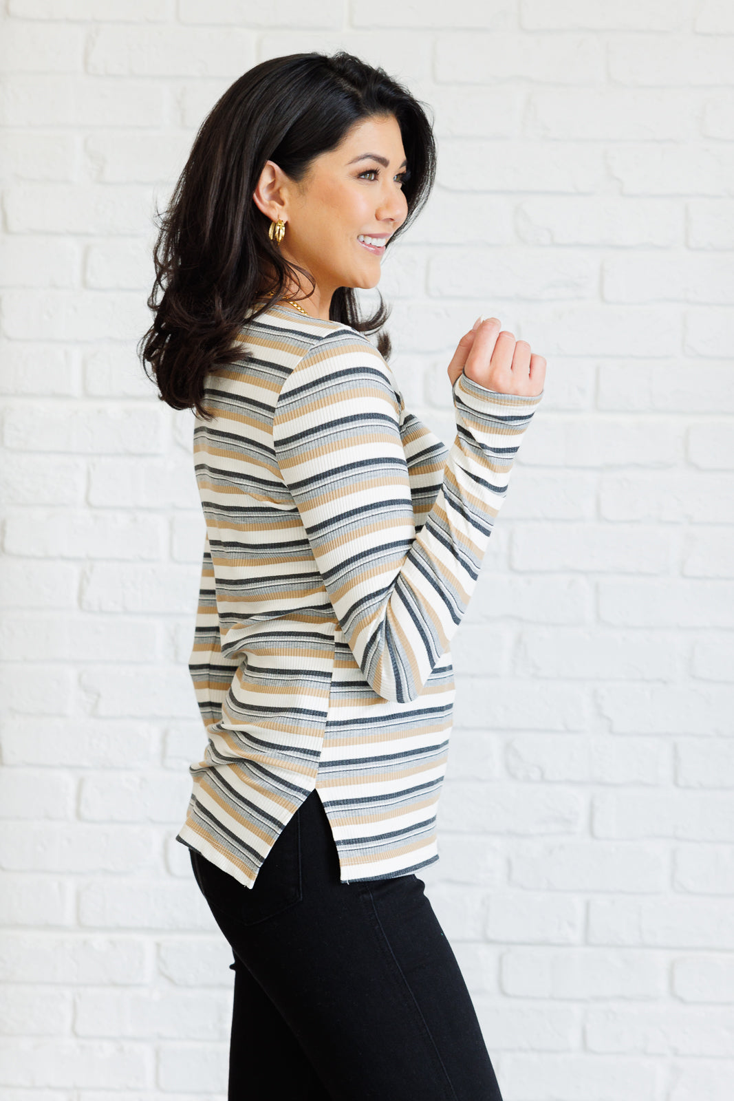 Woman wearing a striped sweater against a white brick wall