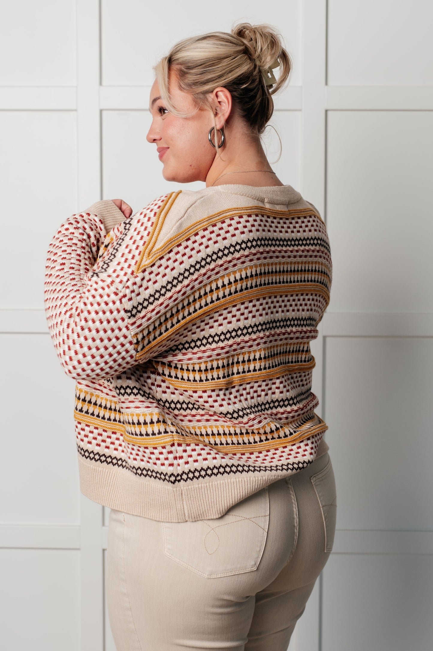 Woman wearing a patterned jacket against a tiled wall