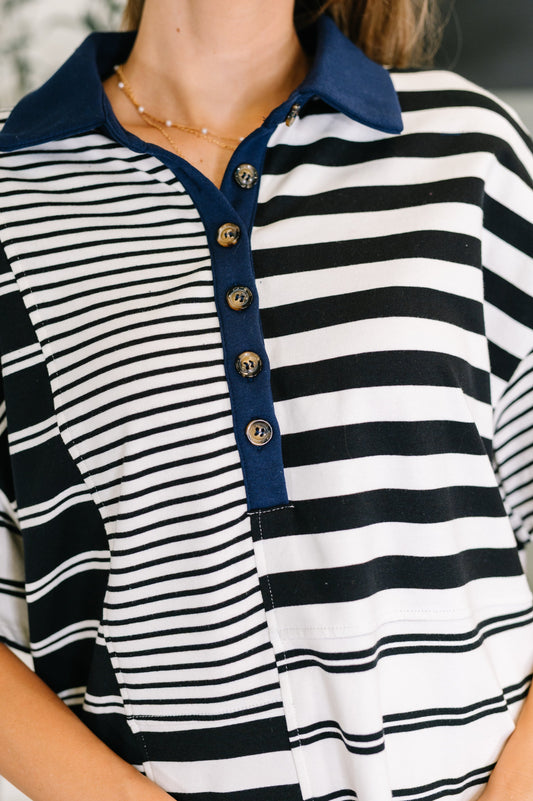 Close-up of a person wearing a black and white striped shirt with a blue collar.