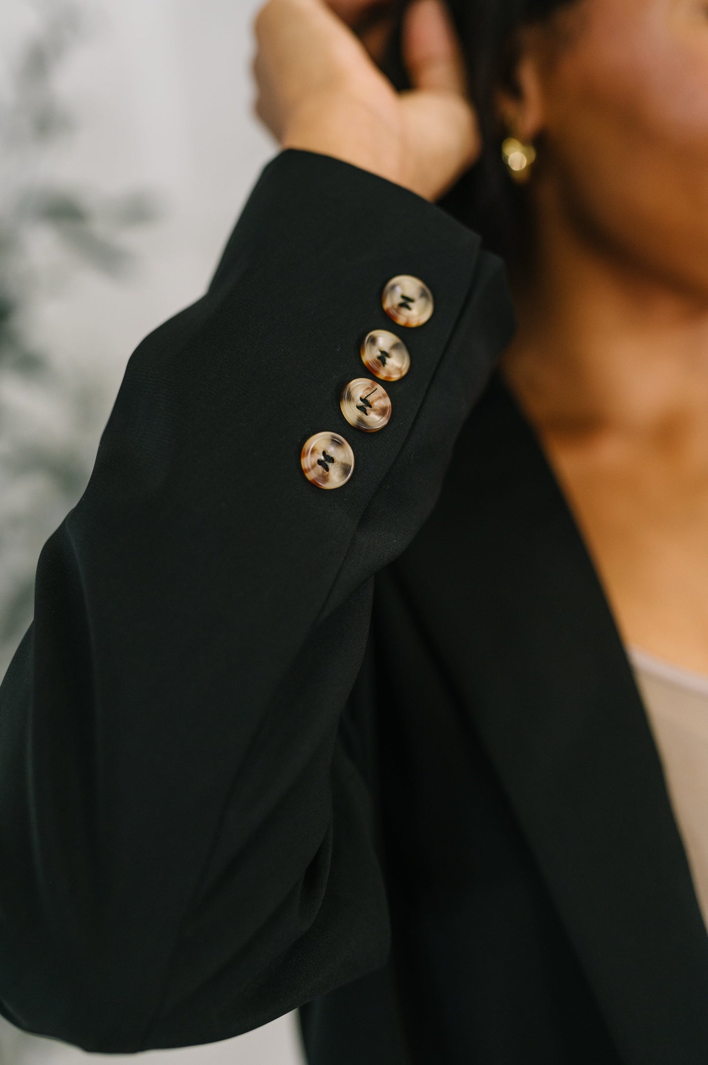 Close-up of a black blazer with gold buttons worn by a person.