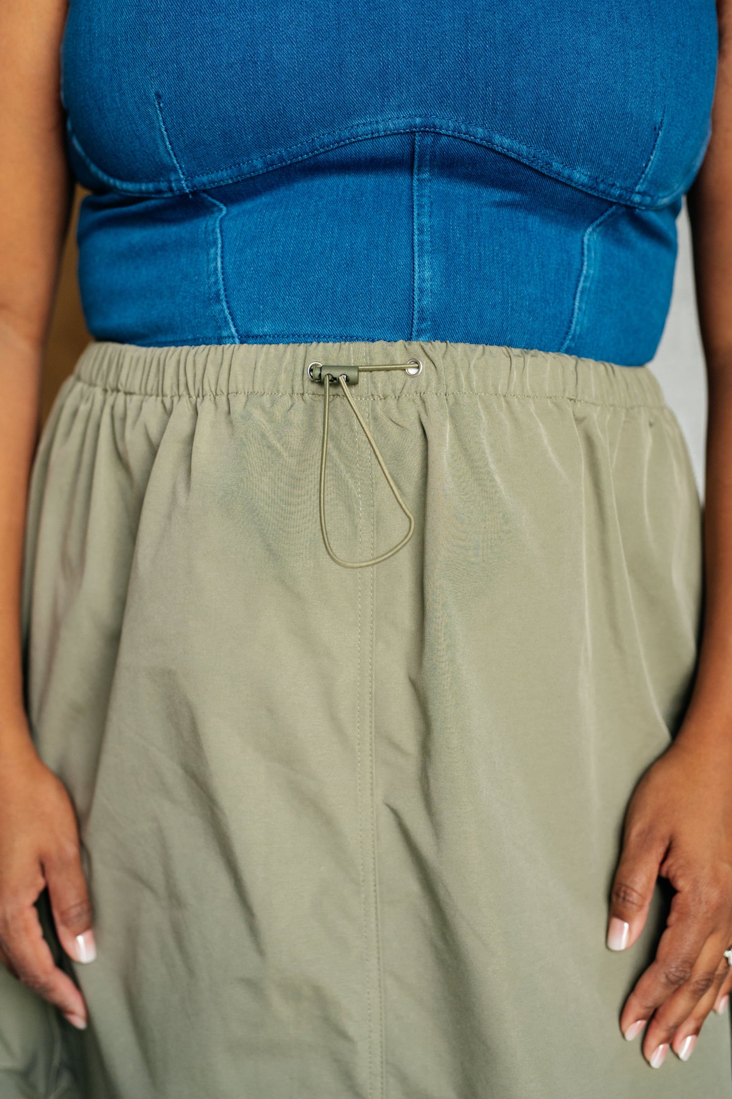 Person wearing a blue top and green pants with a neutral background
