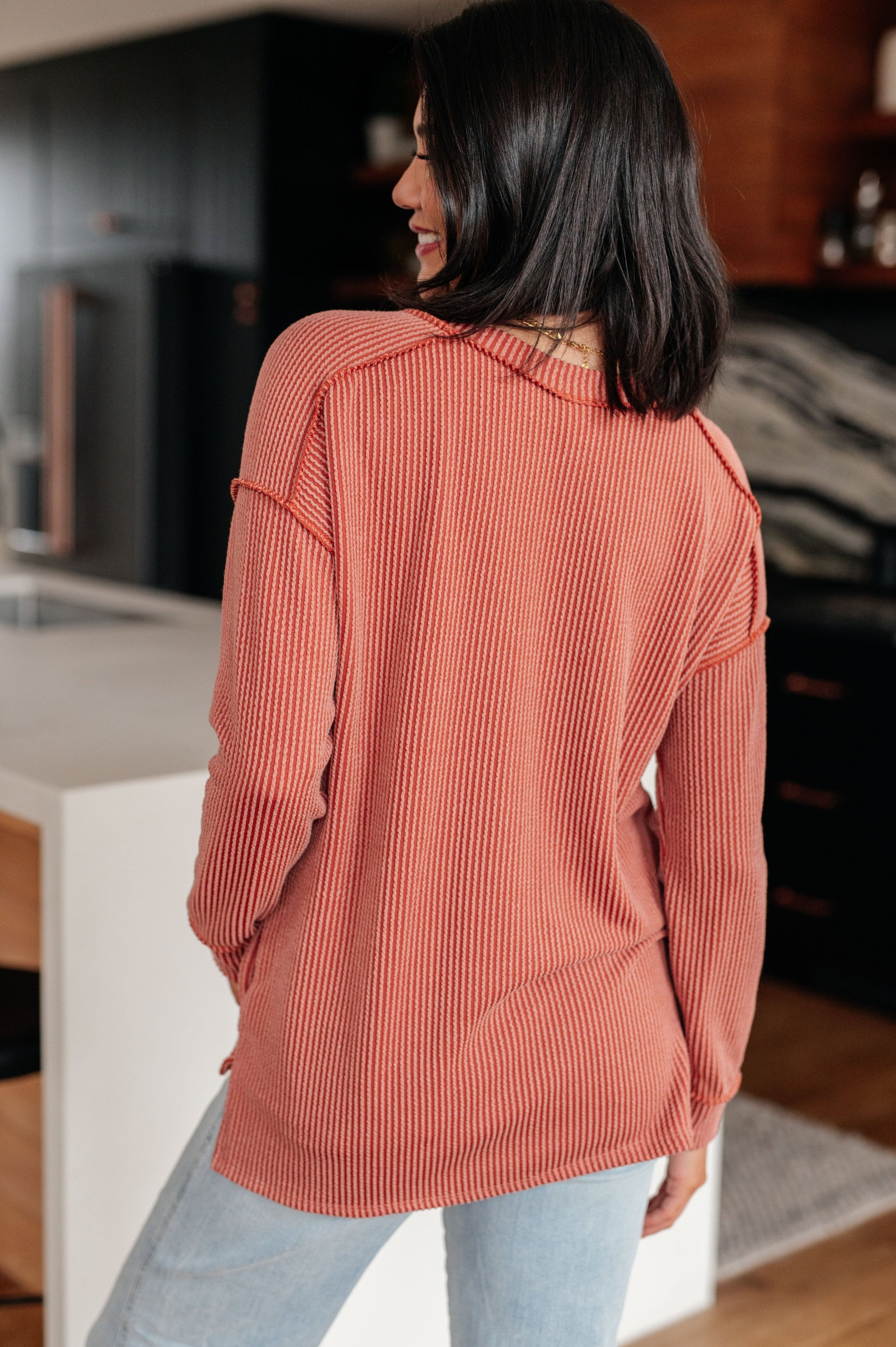 Woman wearing a ribbed sweater in a kitchen setting
