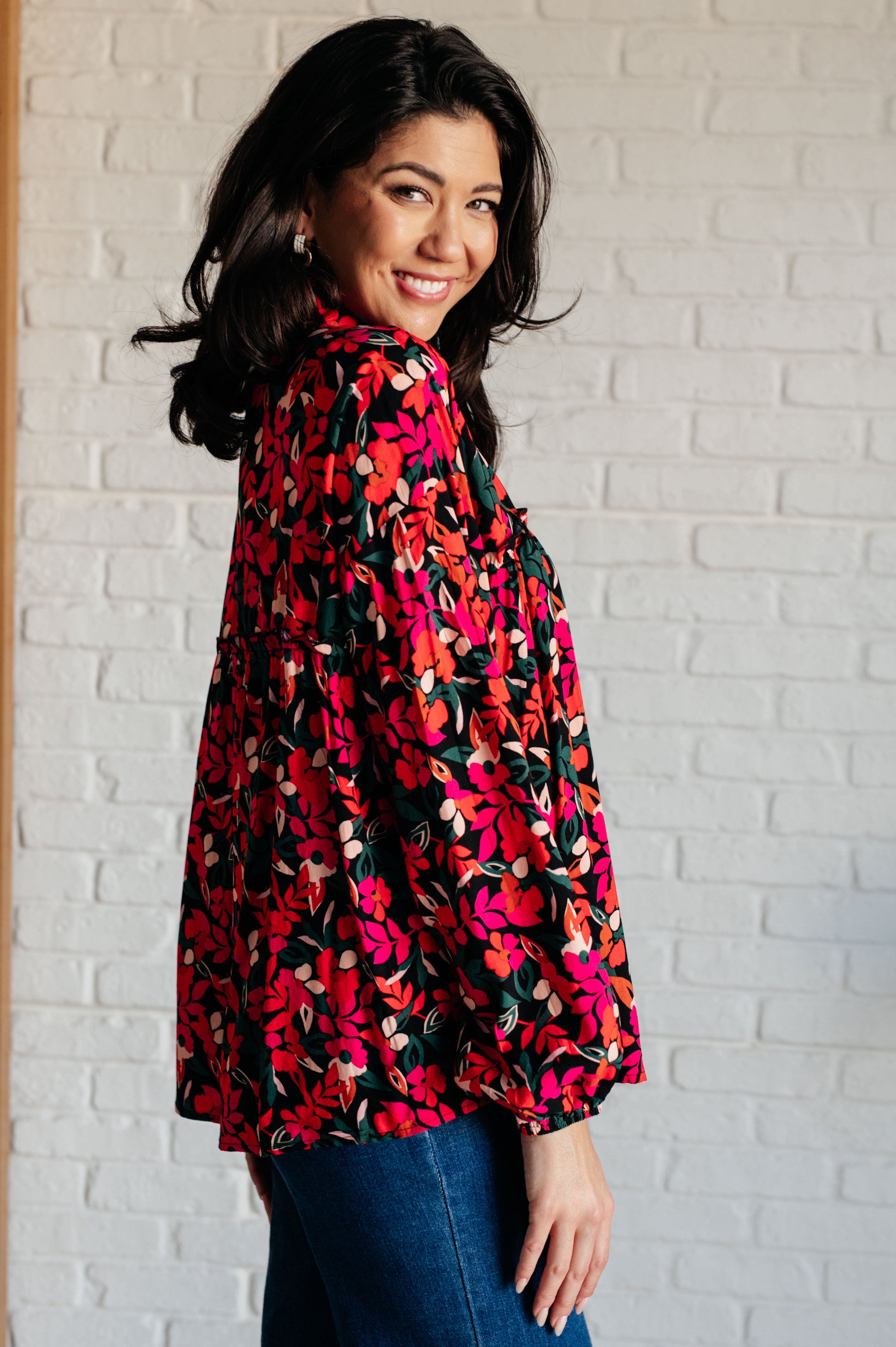Woman wearing a floral blouse in front of a white brick wall
