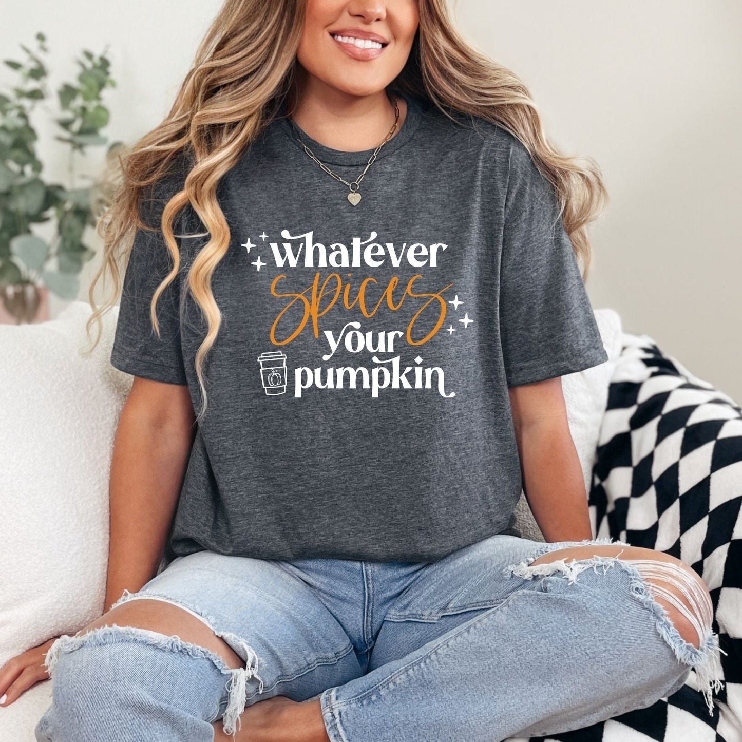 Person wearing a dark gray t-shirt with a humorous pumpkin spice quote, sitting on a couch.