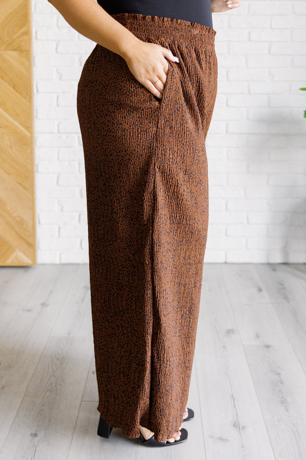 Brown textured pants worn by a person on a light wooden floor.