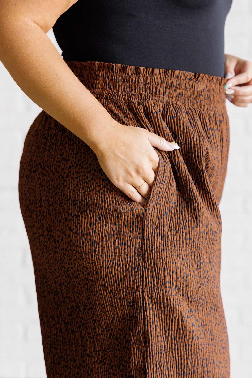 Brown patterned pants worn by a person on a white background