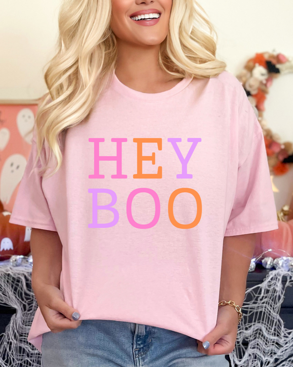 Person wearing a pink 'HEY BOO' t-shirt in a Halloween-themed setting