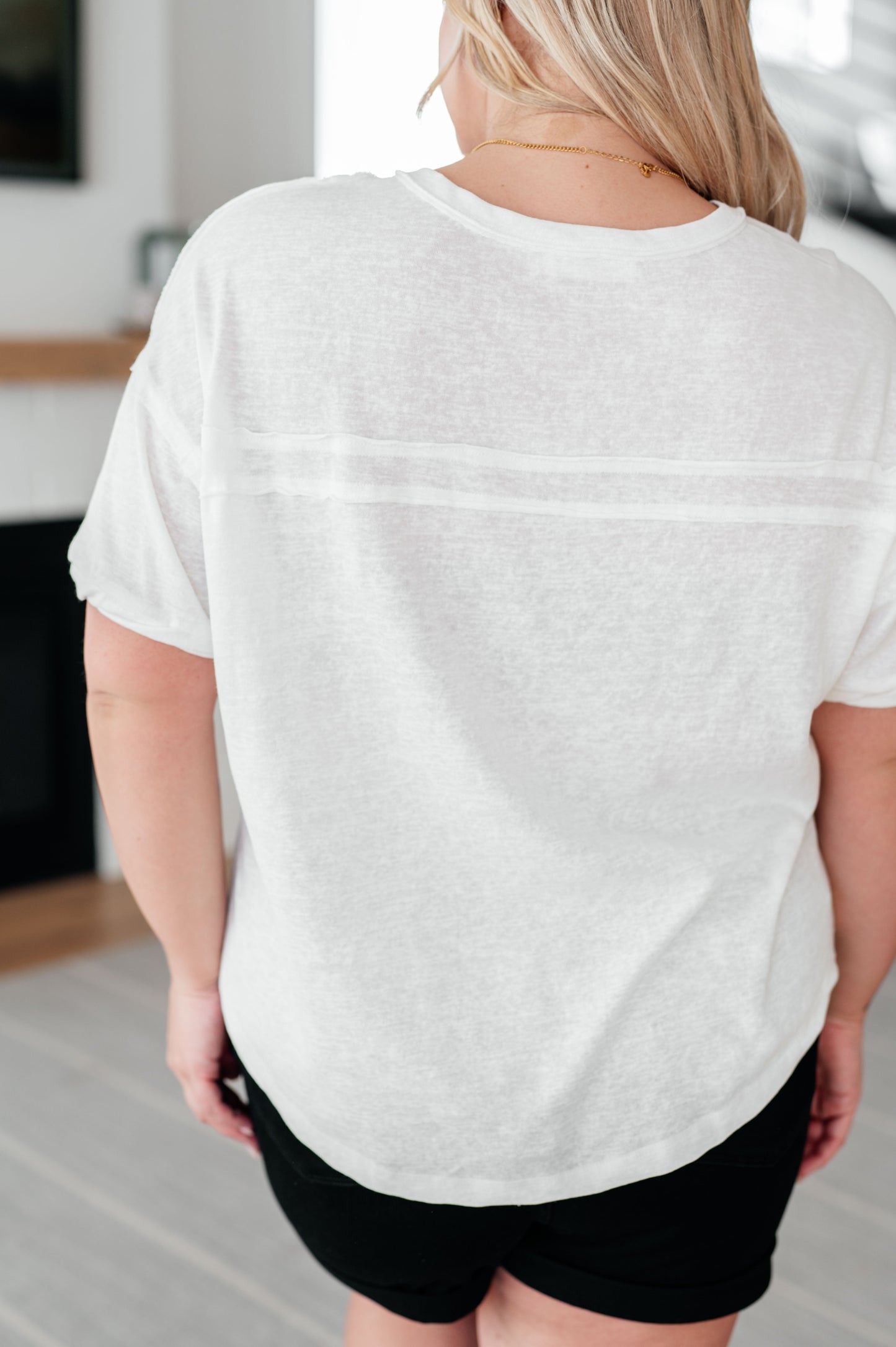 Person wearing a white t-shirt and black shorts in an indoor setting