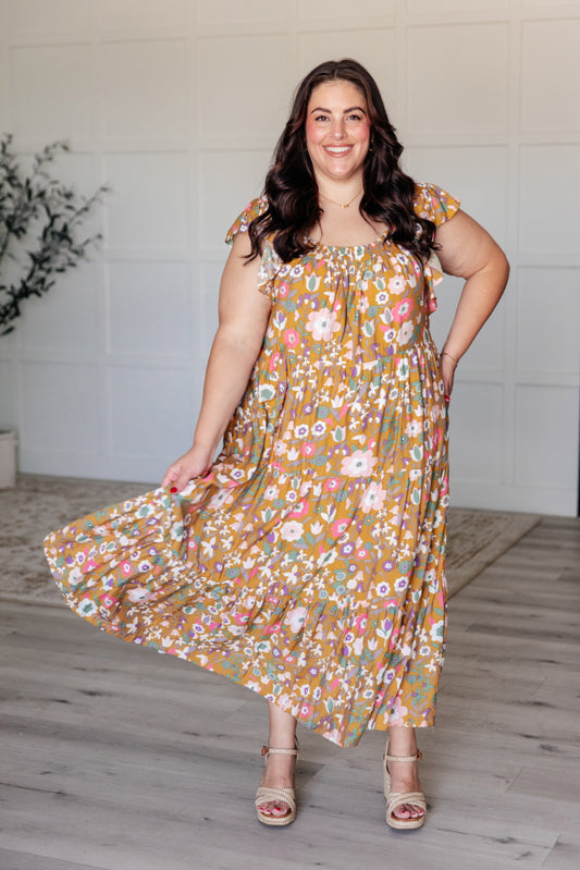 Woman wearing a floral dress standing indoors with a white wall background