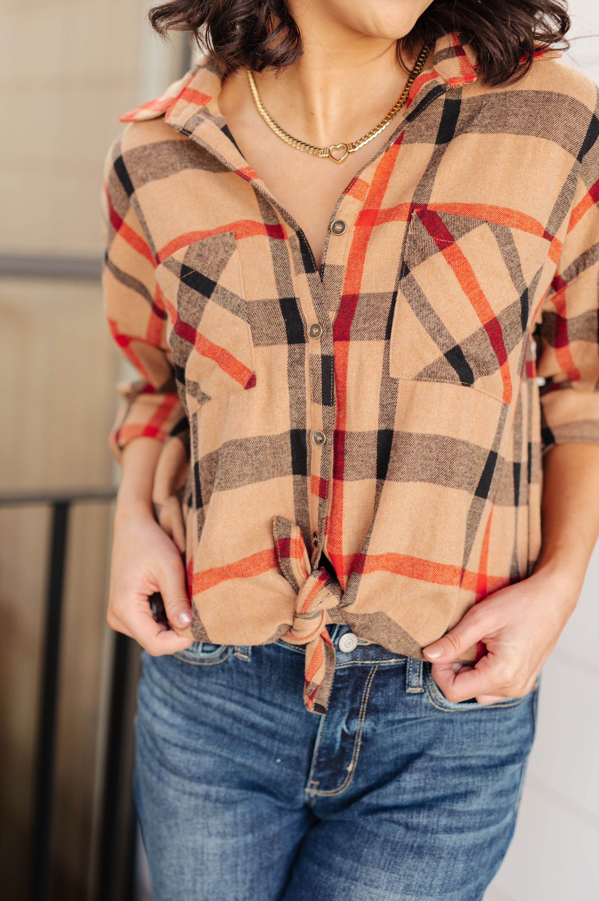 Person wearing a plaid shirt with orange and black patterns and blue jeans.
