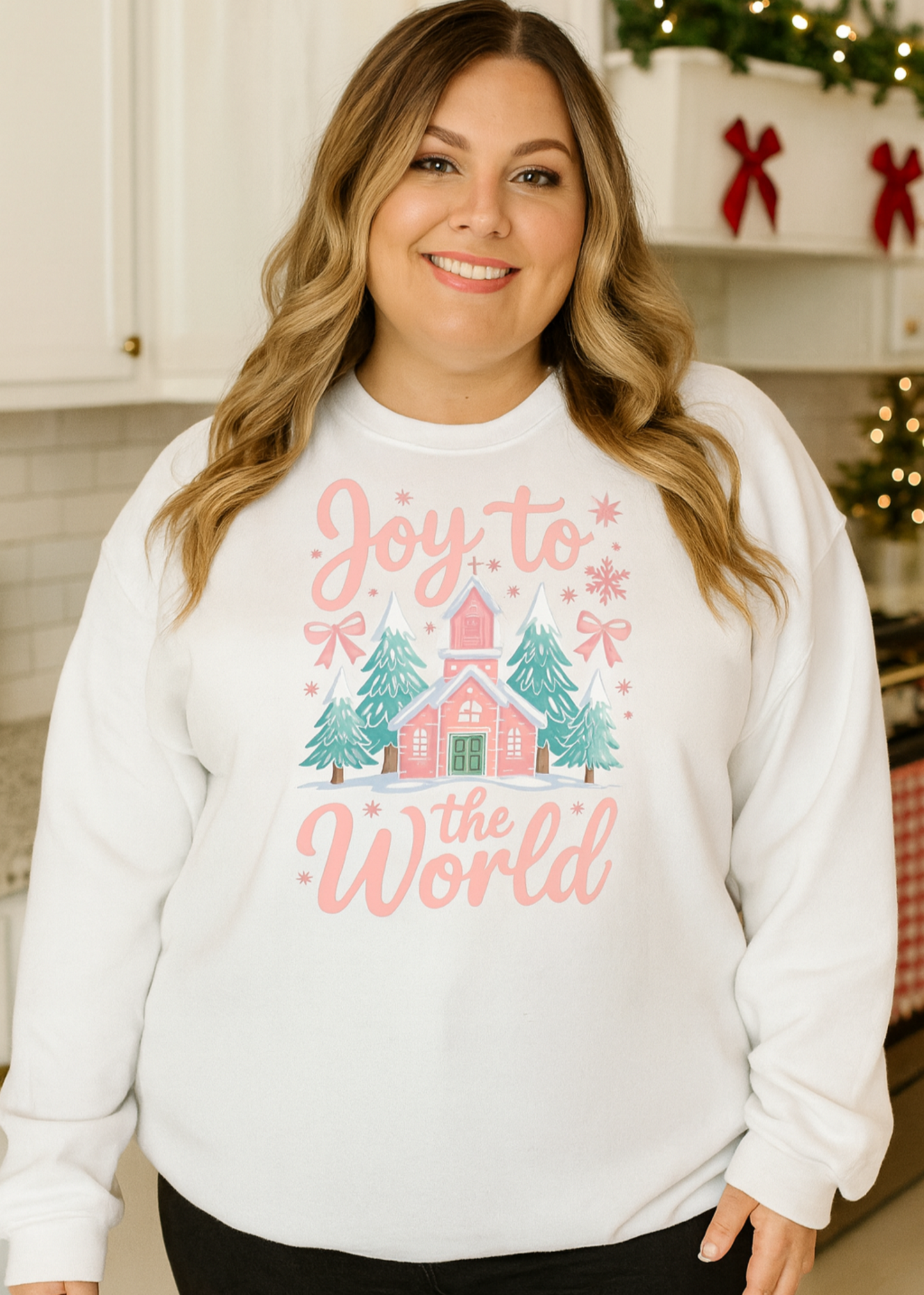 Woman wearing a white sweatshirt with Christmas-themed design in a kitchen.