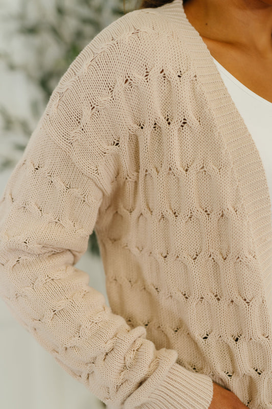 Close-up of a beige knitted cardigan with a blurred background