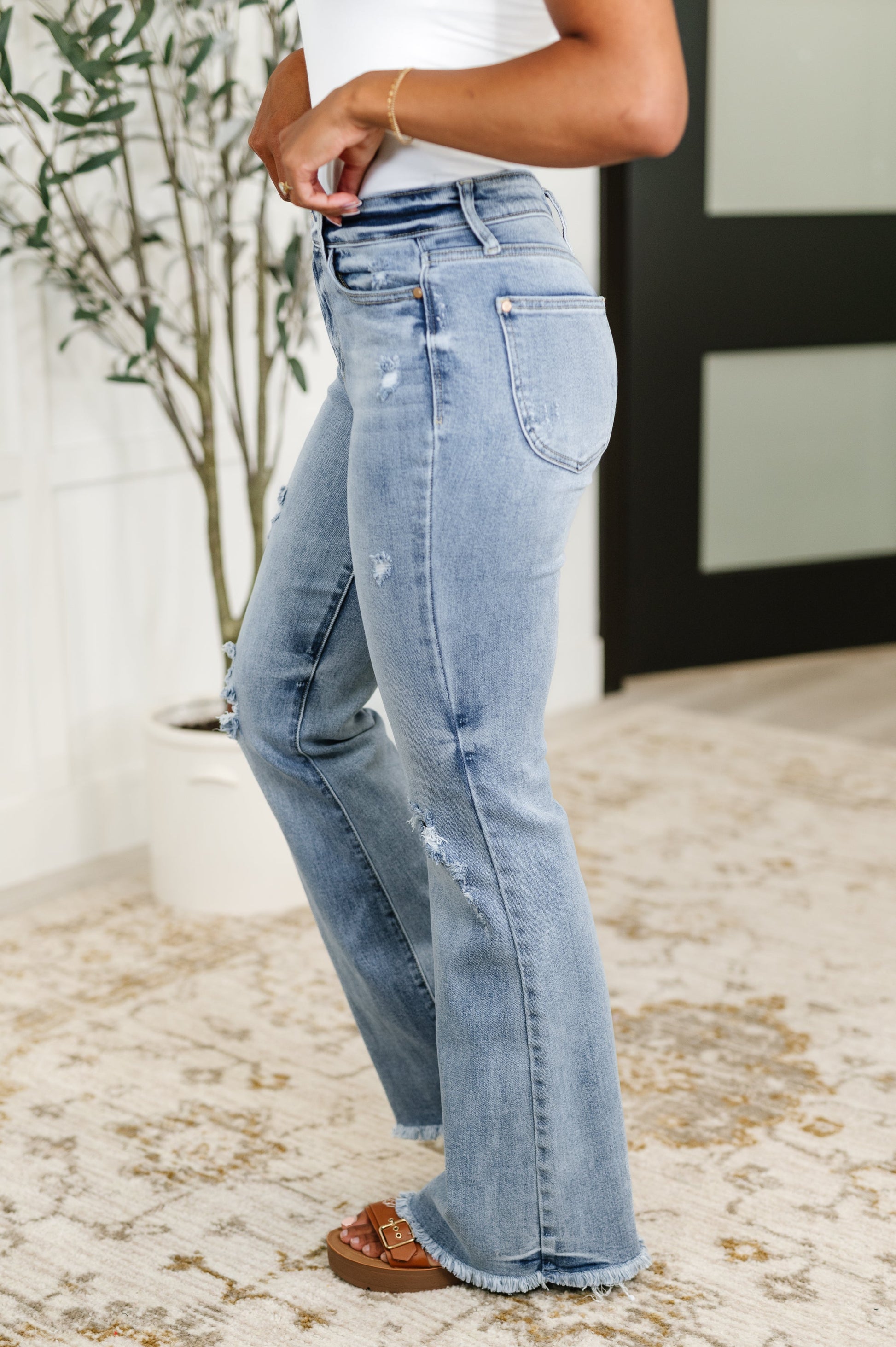 Light blue jeans worn by a person indoors with a plant in the background