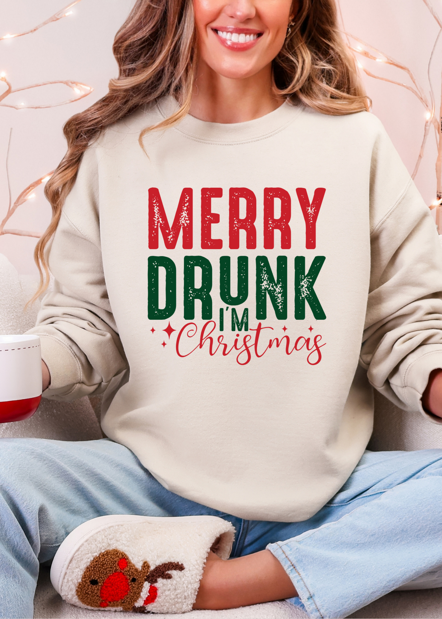 Person wearing a sweater with 'Merry Drunk Christmas' text, holding a mug with a gingerbread man design.