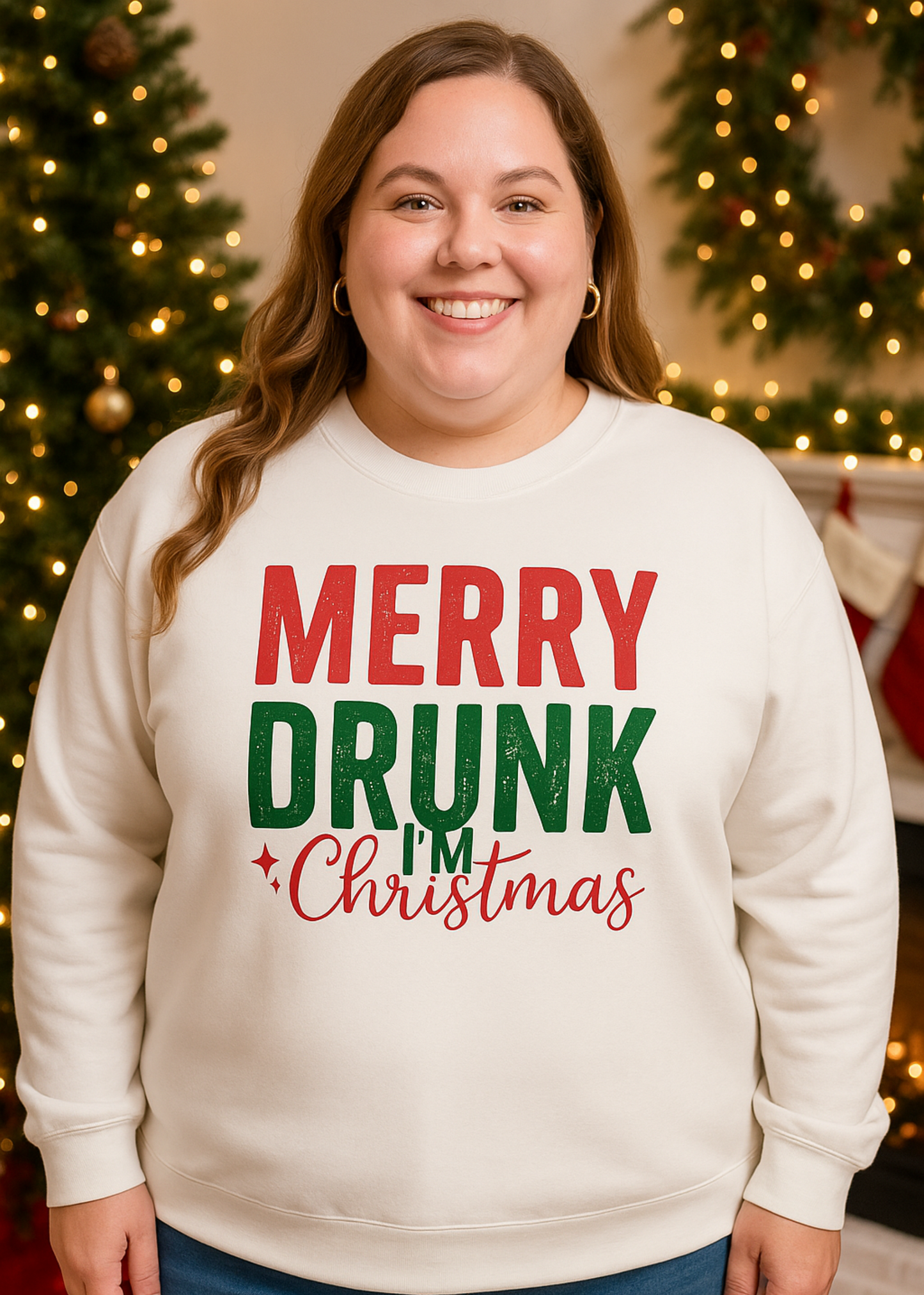 Person wearing a cream sweatshirt with 'Merry Drunk Christmas' text in front of a decorated Christmas tree.