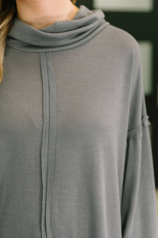 Gray long-sleeve top with a cowl neck on a blurred background