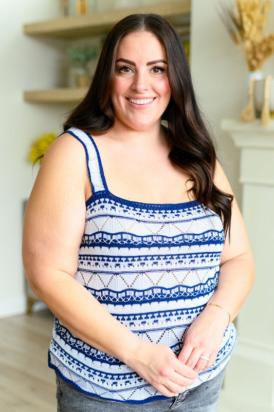 A woman wearing a blue and white geometric patterned tank top with scalloped trim.