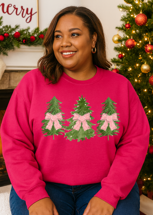 Woman wearing a pink sweater with Christmas tree designs in front of a decorated Christmas tree.